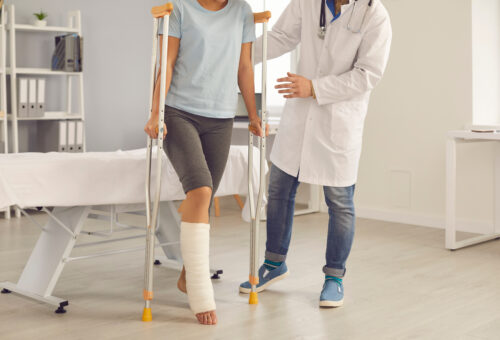 woman injury broken leg crutches doctor helping her